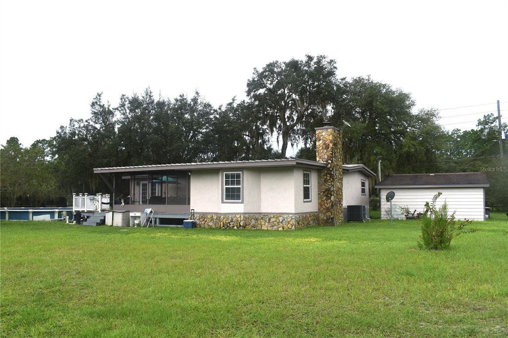 A single-story house with a stone chimney, a screened-in porch, and a detached garage — 15355 SW 85TH AVENUE, DUNNELLON, FL