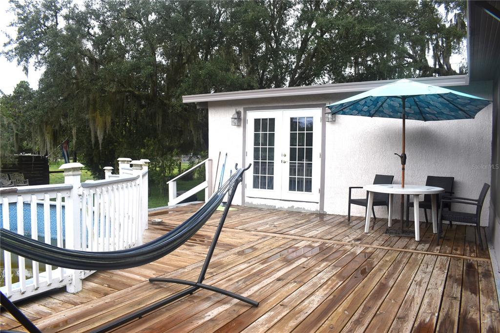 A wooden deck features a hammock, a patio table with an umbrella, and double doors — 15355 SW 85TH AVENUE, DUNNELLON, FL