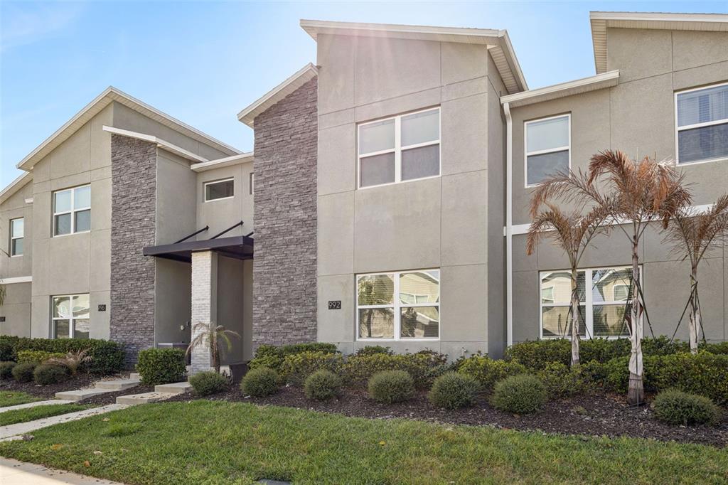 A two-story townhouse exterior features gray stucco walls, stone accents, and a covered entryway — 992 LEADER STREET, DAVENPORT, FL
