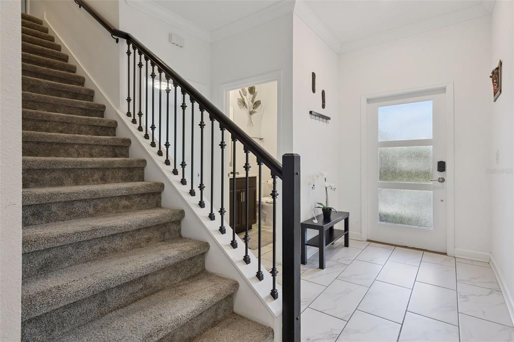 A carpeted staircase with a black metal railing leads up from a tiled entryway — 992 LEADER STREET, DAVENPORT, FL