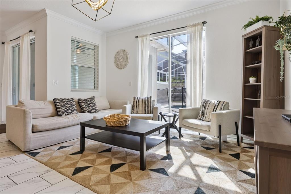 A living room features a beige sofa, two armchairs, a coffee table, and a patterned rug — 992 LEADER STREET, DAVENPORT, FL