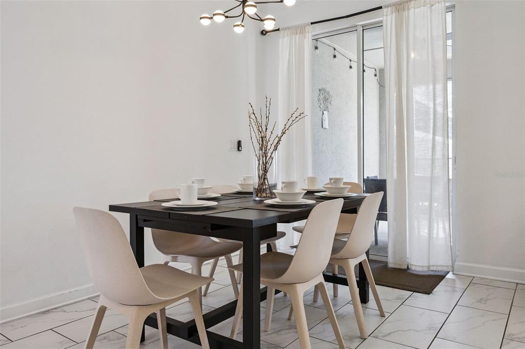 A dining room features a dark table, light chairs, tile flooring, and a sliding glass door — 992 LEADER STREET, DAVENPORT, FL