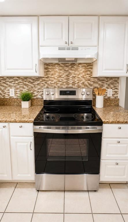 A kitchen features white cabinets, a stainless steel electric range, and a mosaic tile backsplash — 9919 TURF COURT UNIT 3, ORLANDO, FL
