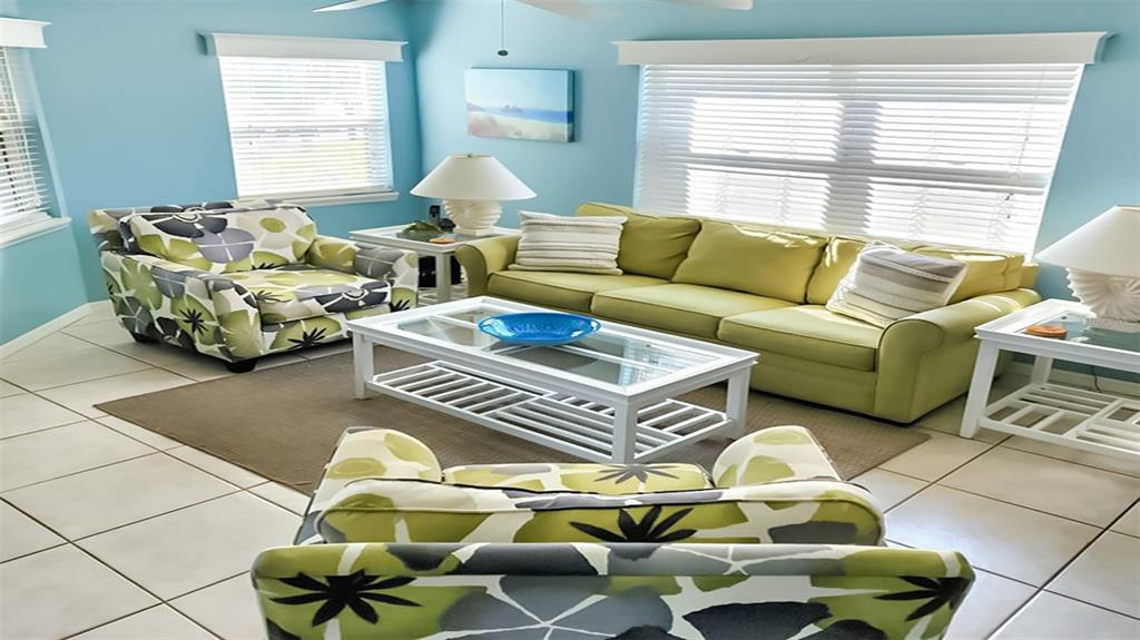 A living room features a green sofa, patterned armchairs, a white coffee table, and blue walls — 1226 SIESTA BAYSIDE DRIVE UNIT 1226-C, SARASOTA, FL