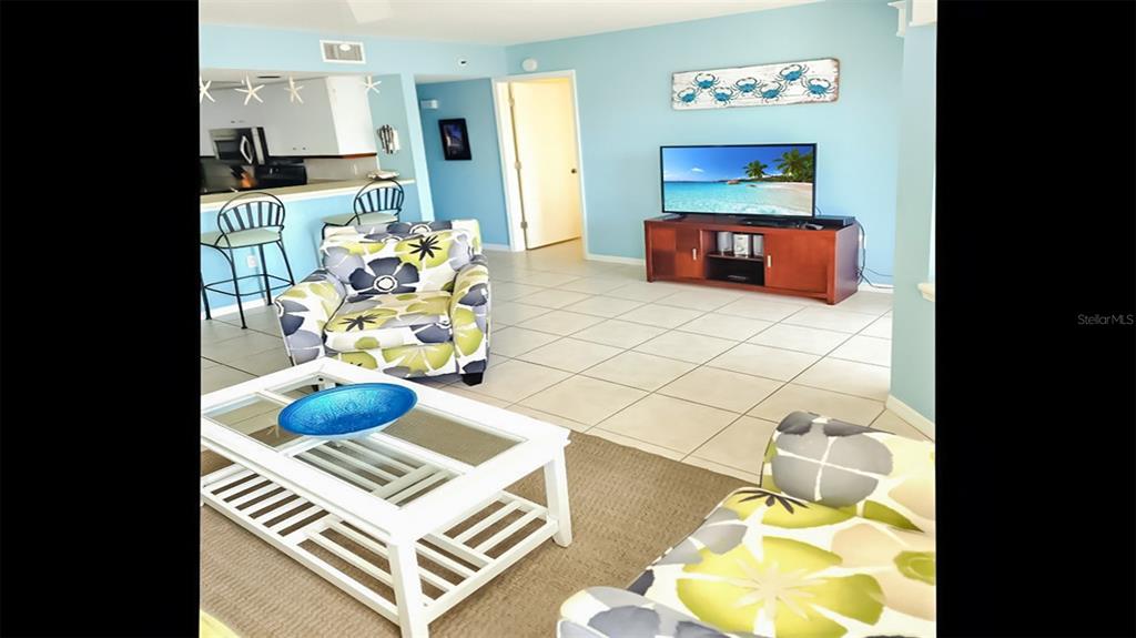 A living room features light blue walls, tile flooring, a patterned armchair, and a coffee table — 1226 SIESTA BAYSIDE DRIVE UNIT 1226-C, SARASOTA, FL
