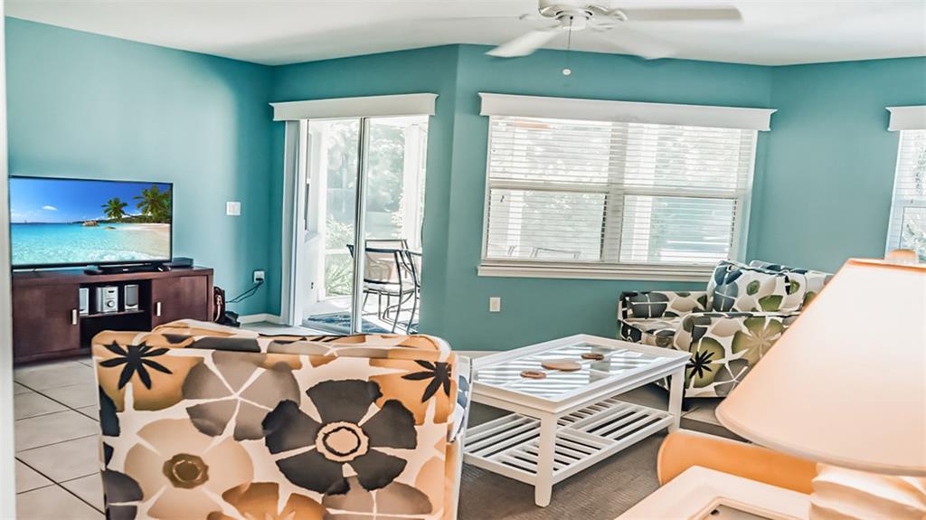 A living room features teal walls, patterned armchairs, a white coffee table, and a television — 1226 SIESTA BAYSIDE DRIVE UNIT 1226-C, SARASOTA, FL
