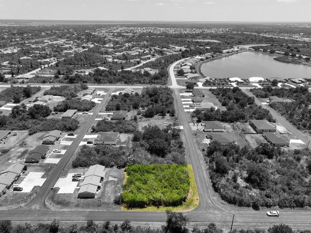 An aerial view shows a vacant, rectangular lot highlighted in green within a residential neighborhood — 12204 KIRK AVENUE, PORT CHARLOTTE, FL