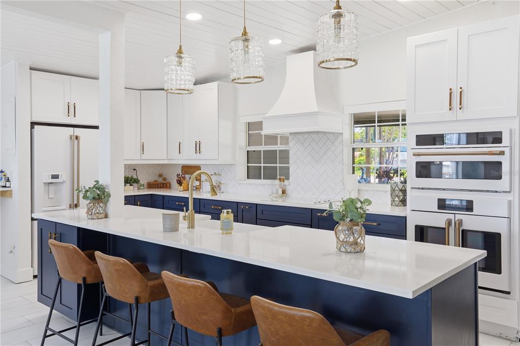 A kitchen features a large blue island with white countertops, gold fixtures, and four stools — 5716 MOONLIGHT CIRCLE, ORLANDO, FL