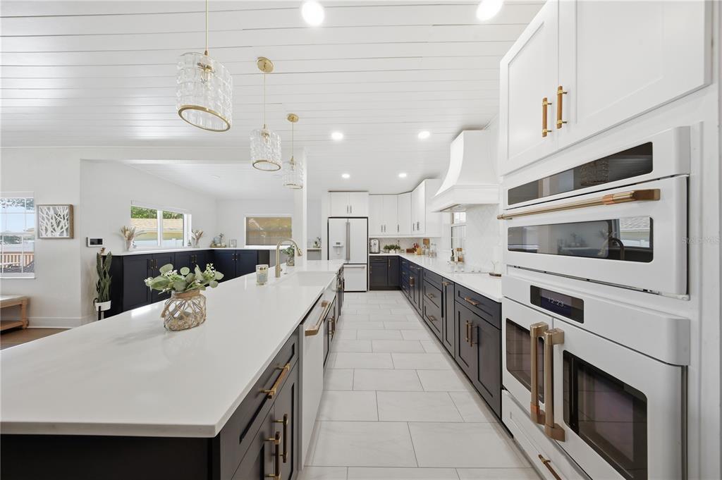 A modern kitchen features dark lower cabinets, white upper cabinets, a large island, and white appliances — 5716 MOONLIGHT CIRCLE, ORLANDO, FL