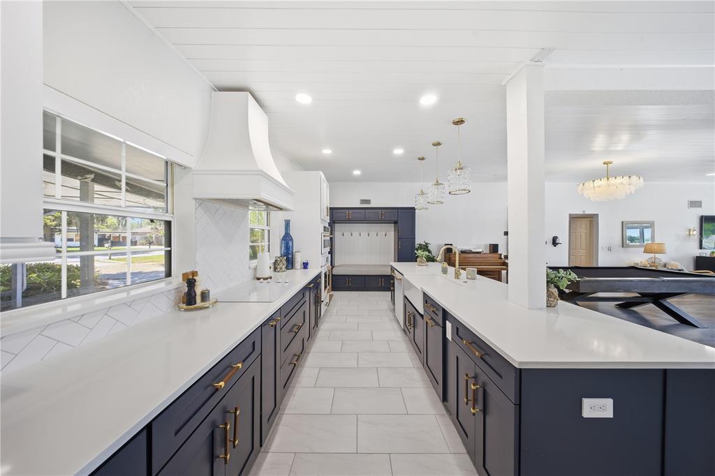 A modern kitchen features dark blue cabinets, white countertops, and a white range hood — 5716 MOONLIGHT CIRCLE, ORLANDO, FL