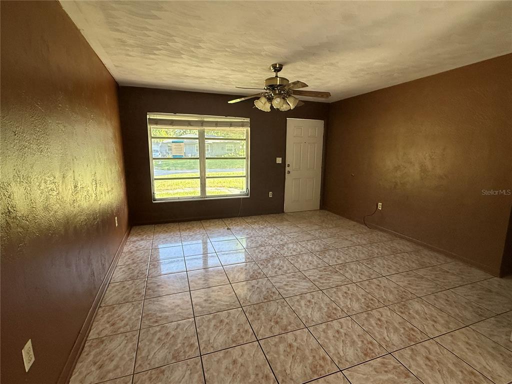 A room with brown walls, a ceiling fan, and light-colored tiled flooring — 3802 E ESTHER STREET, ORLANDO, FL