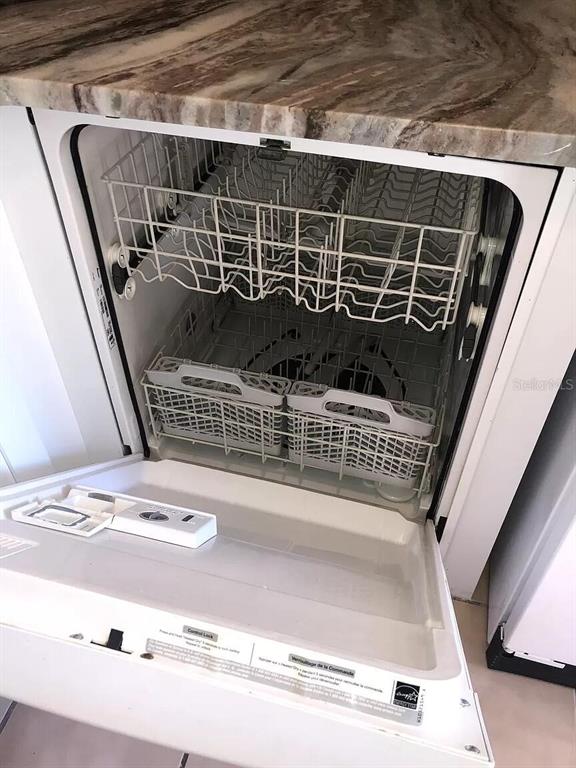 An open dishwasher with two racks and a silverware basket sits under a marble countertop — 10109 BLAZED TREE COURT, ORLANDO, FL