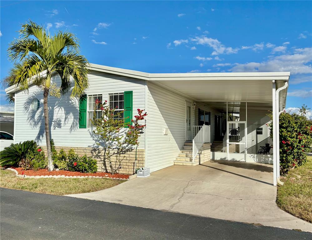 A single-story mobile home with white siding, green shutters, and a covered carport — 6727 MT PLEASANT ROAD NE UNIT 53, ST PETERSBURG, FL