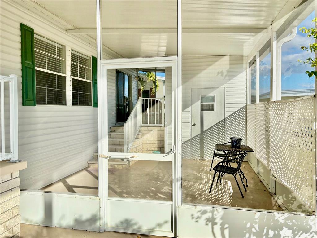 A screened-in porch features a small table, two chairs, and a white door — 6727 MT PLEASANT ROAD NE UNIT 53, ST PETERSBURG, FL