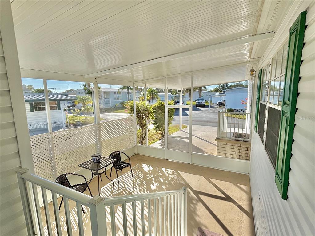 A screened-in porch features a small table with two chairs and a white railing — 6727 MT PLEASANT ROAD NE UNIT 53, ST PETERSBURG, FL