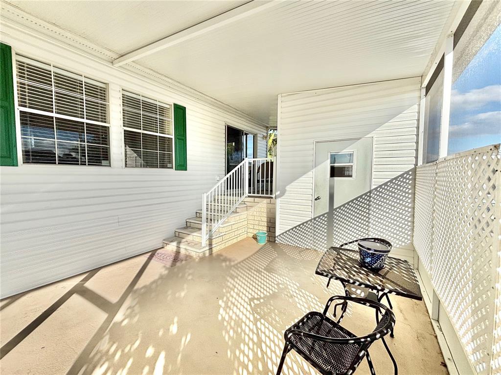 A covered patio features a small table, two chairs, brick steps, and a storage door — 6727 MT PLEASANT ROAD NE UNIT 53, ST PETERSBURG, FL