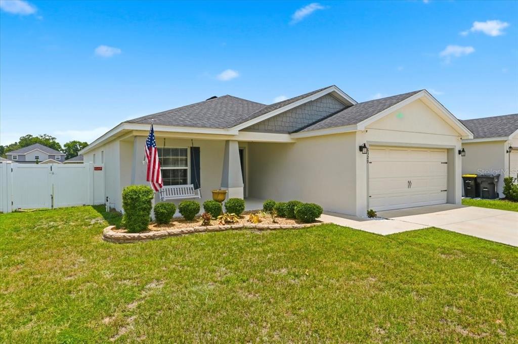 A single-story house with a white garage, a front porch swing, and a landscaped yard — 6329 GARDNER DRIVE, LAKELAND, FL