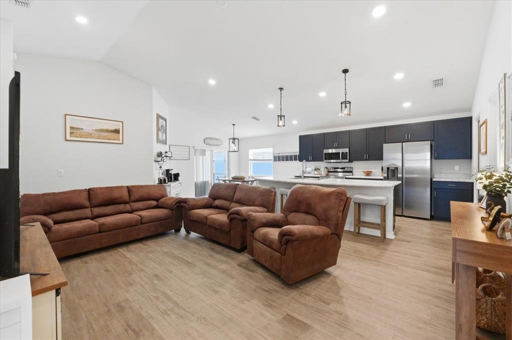 An open-concept living room features brown furniture, wood-look flooring, and a kitchen with dark cabinets — 6329 GARDNER DRIVE, LAKELAND, FL