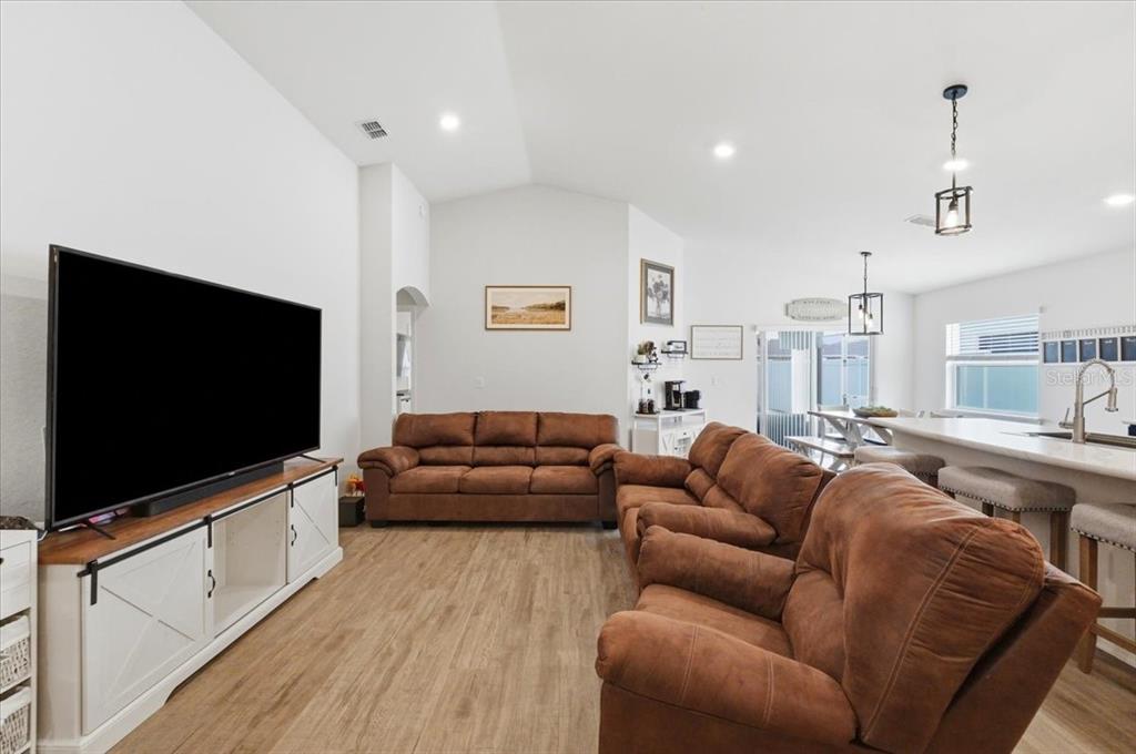A living room with brown sofas, a large television, and wood-look flooring — 6329 GARDNER DRIVE, LAKELAND, FL