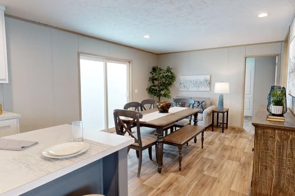 A dining area with a wooden table, chairs, a bench, and sliding glass doors — 19359 NW 274TH STREET, OKEECHOBEE, FL