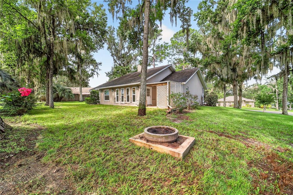 A single-story house with a concrete fire pit in the grassy front yard — 4849 NW 83RD COURT, OCALA, FL