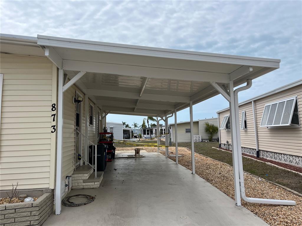 A covered carport with a concrete floor is attached to the side of a house — 873 BAVENO DRIVE, VENICE, FL