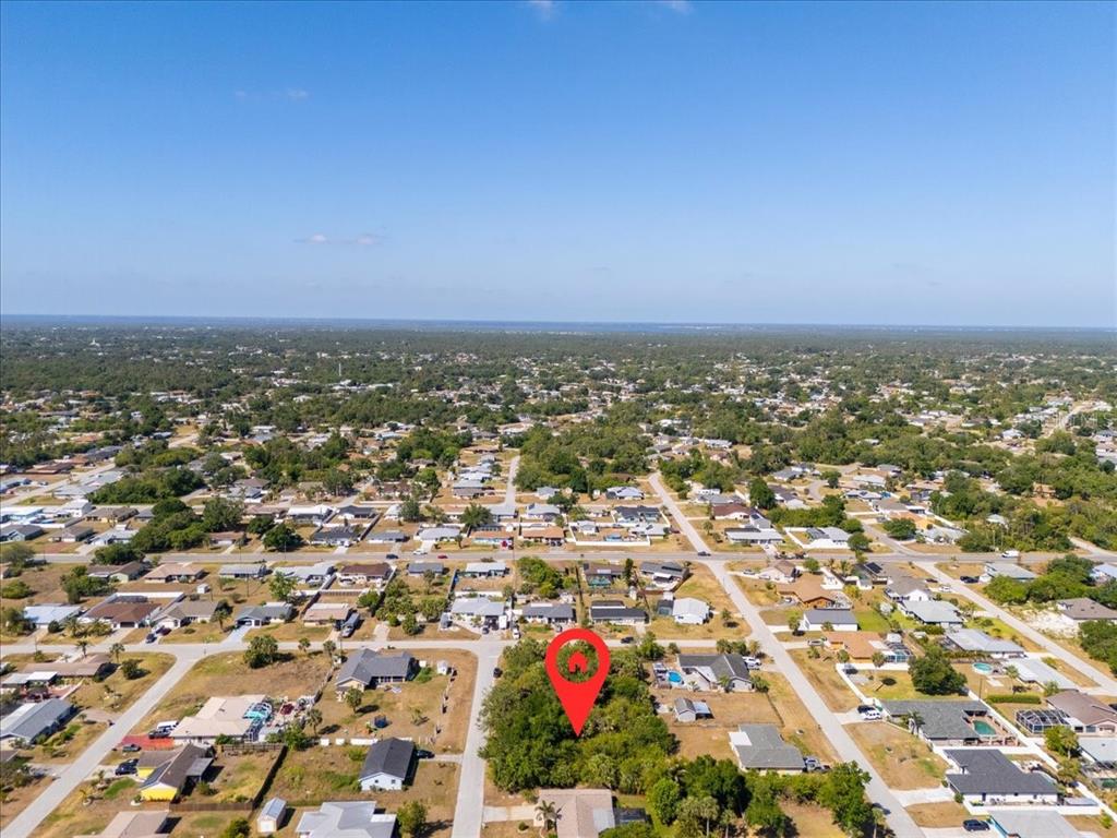 An aerial view shows a wooded residential lot marked with a red pin — 868 MENSH TERRACE NW, PORT CHARLOTTE, FL