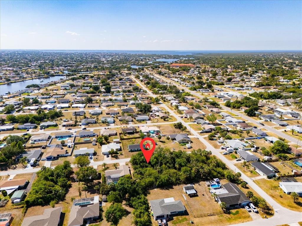 An aerial view shows a residential neighborhood with a red pin marking a vacant lot — 868 MENSH TERRACE NW, PORT CHARLOTTE, FL