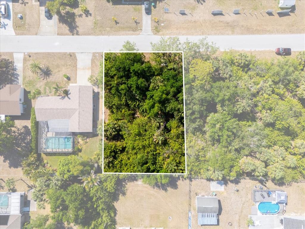 An aerial view shows a rectangular, tree-covered vacant lot outlined in white between two houses — 868 MENSH TERRACE NW, PORT CHARLOTTE, FL
