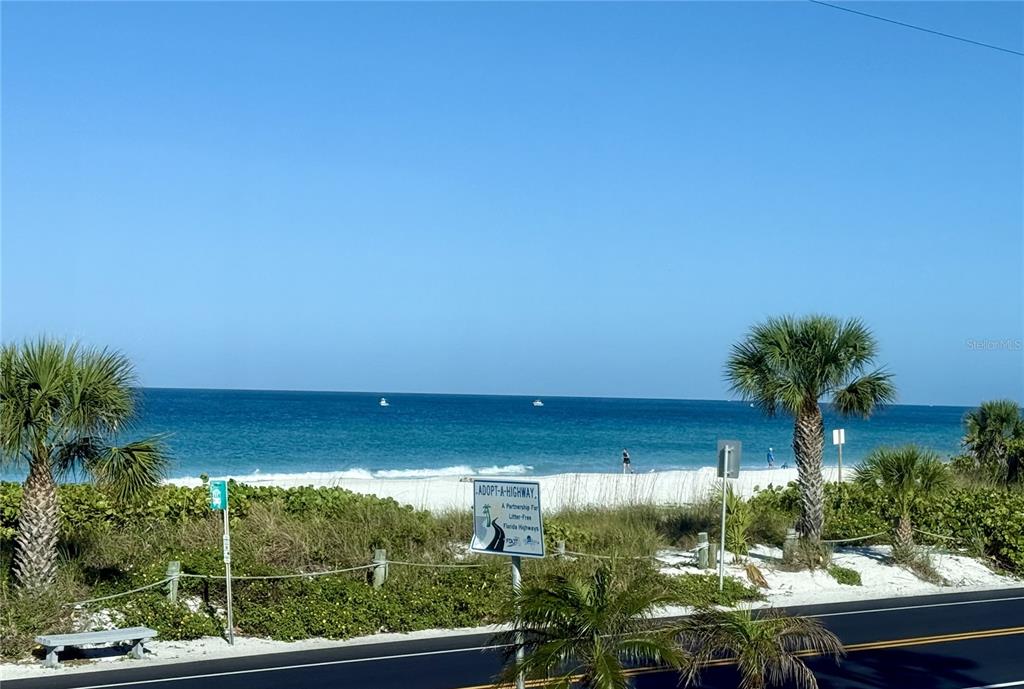 An outdoor view of a beach with palm trees, a road, and a highway sign — 1007 GULF DRIVE N UNIT 106, BRADENTON BEACH, FL