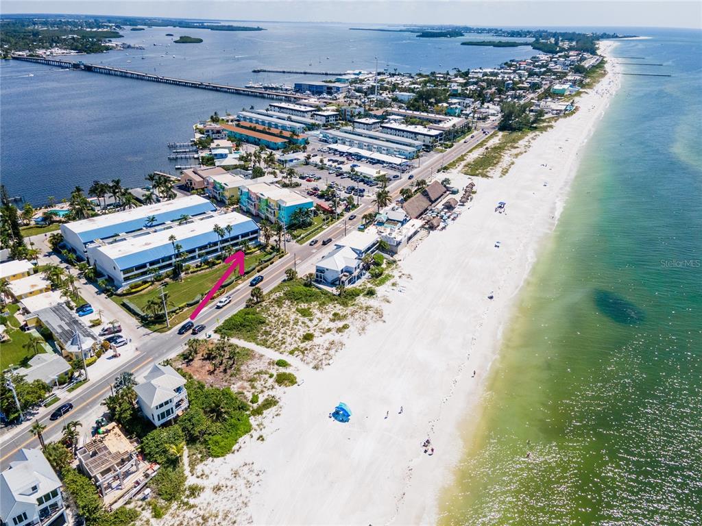 An aerial view shows a beachfront resort complex with a multi-story building and parking — 1007 GULF DRIVE N UNIT 106, BRADENTON BEACH, FL