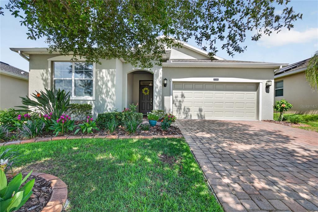 A single-story house with a beige stucco exterior, a two-car garage, and a paved driveway — 3548 KINLEY BROOKE LANE, CLERMONT, FL