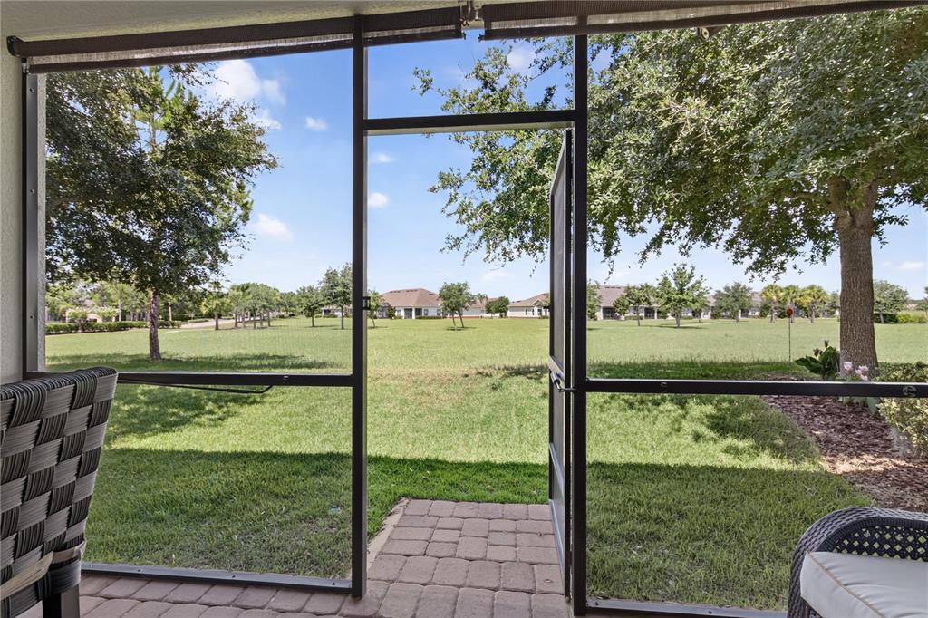 A view from a screened-in patio looking out onto a grassy lawn and neighborhood houses — 3548 KINLEY BROOKE LANE, CLERMONT, FL