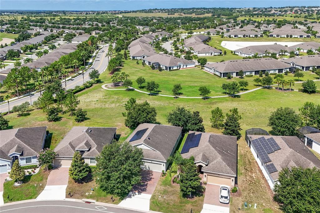 An aerial view shows several suburban houses with solar panels and a curved walking path — 3548 KINLEY BROOKE LANE, CLERMONT, FL