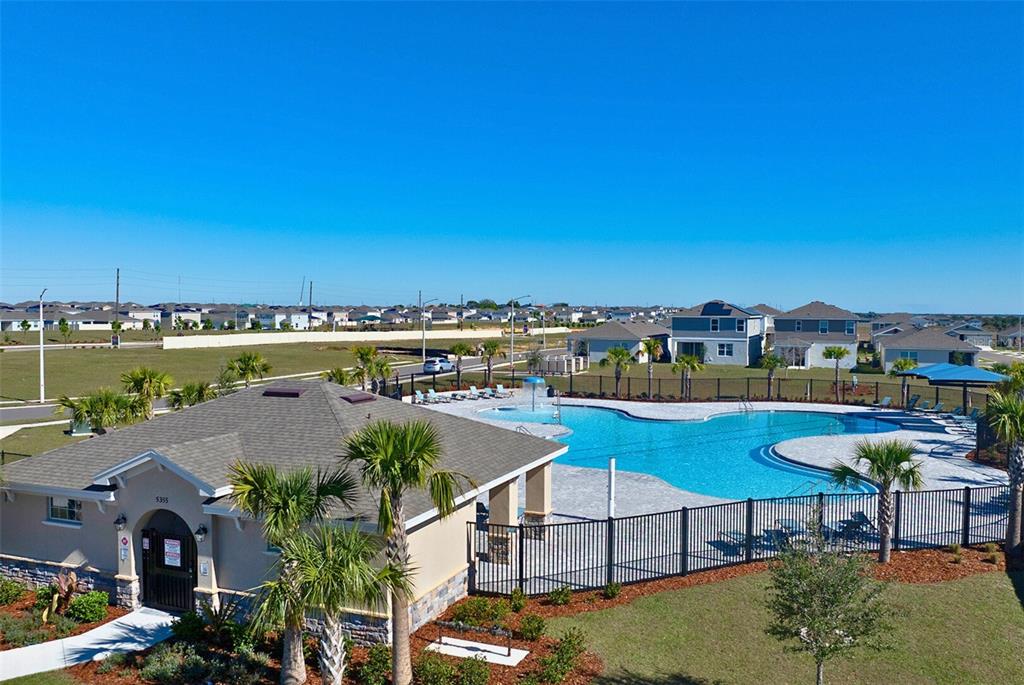 An aerial view shows a community swimming pool and clubhouse surrounded by a black fence — 1755 VANILLA STREET, HAINES CITY, FL