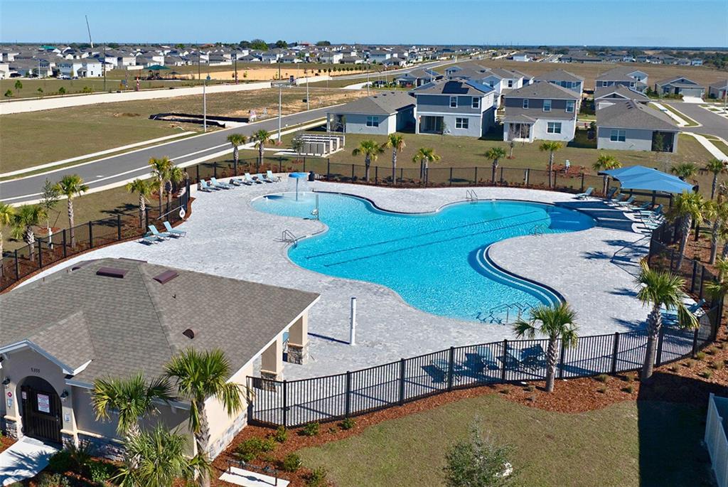 An aerial view shows a community swimming pool with a clubhouse and surrounding residential homes — 1755 VANILLA STREET, HAINES CITY, FL