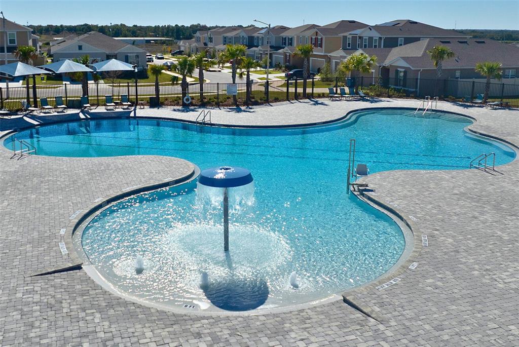 A large community swimming pool with a mushroom fountain and surrounding patio in a residential neighborhood — 1755 VANILLA STREET, HAINES CITY, FL