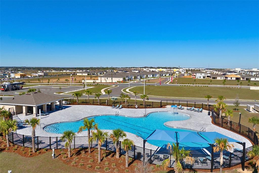 An aerial view shows a community swimming pool with a shaded area and adjacent clubhouse — 1755 VANILLA STREET, HAINES CITY, FL