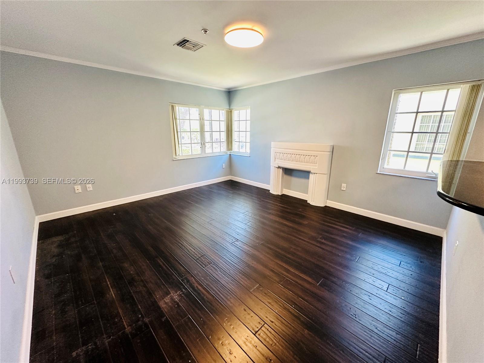 An empty room features light blue walls, dark hardwood floors, and a white decorative fireplace — 600 Euclid Ave # 4B, Miami Beach FL 33139, MIAMI BEACH, FL