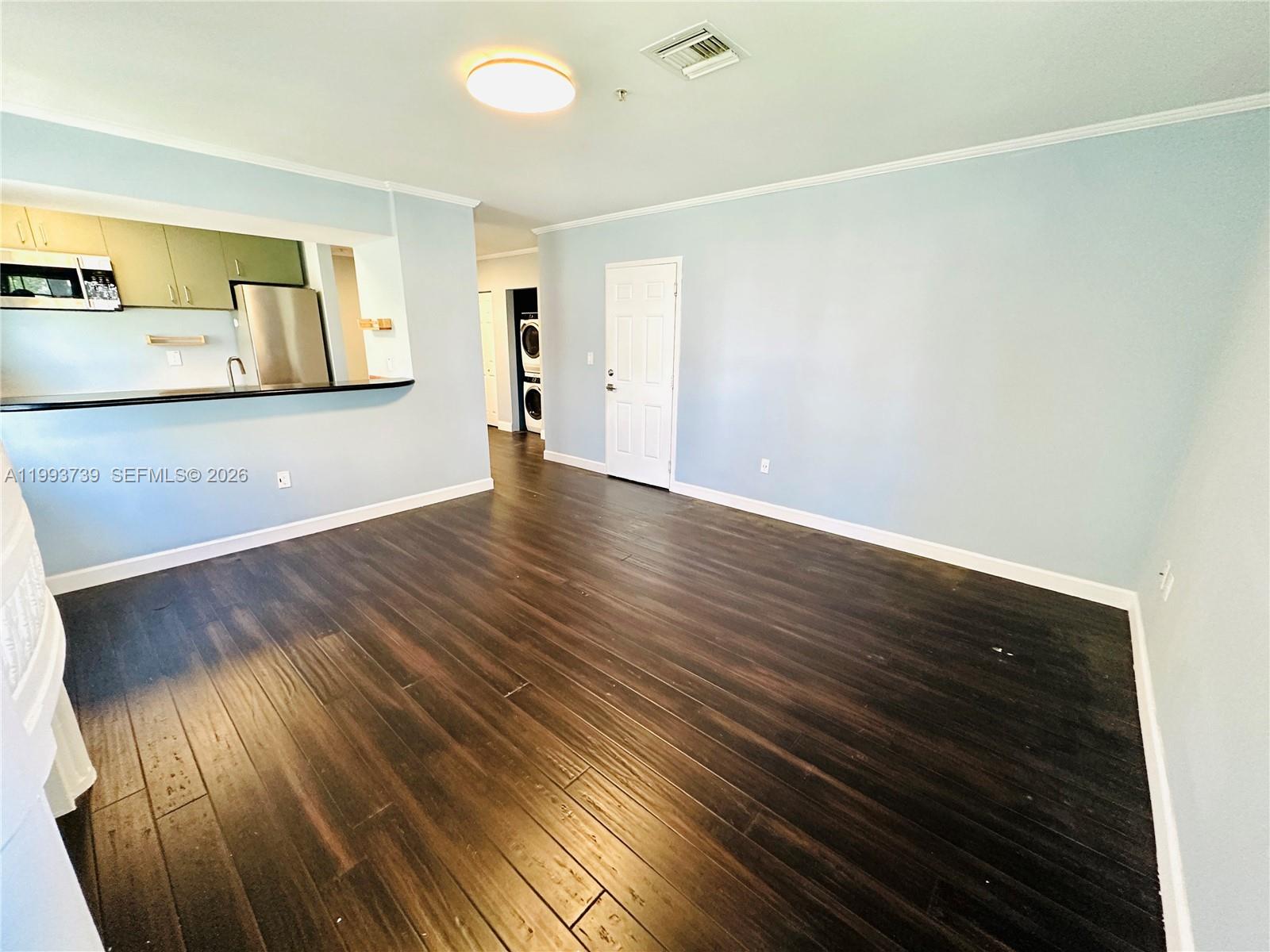 An open living area features light blue walls, dark wood flooring, and a kitchen pass-through — 600 Euclid Ave # 4B, Miami Beach FL 33139, MIAMI BEACH, FL
