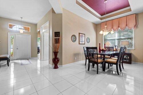 A dining room with white tile floors, a tray ceiling, and a wooden table set — 7940 Rockford Road, Boynton Beach FL 33472, BOYNTON BEACH, FL