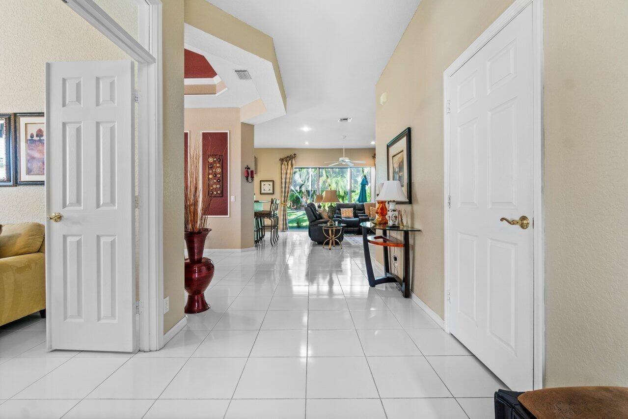 A tiled hallway leads from the entryway into a living room with large glass doors — 7940 Rockford Road, Boynton Beach FL 33472, BOYNTON BEACH, FL