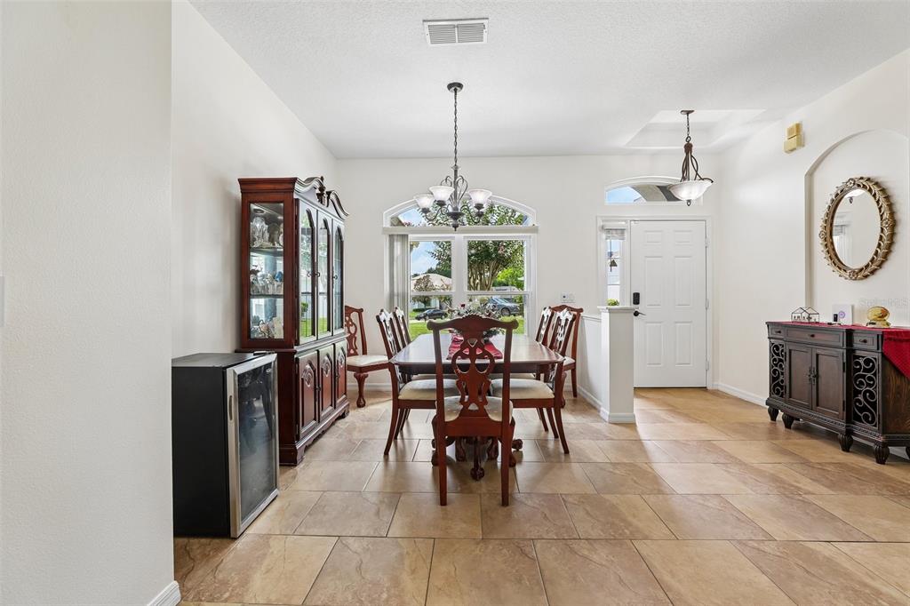 A dining room features tile flooring, a wooden table with chairs, and a matching hutch — 2025 WINTERMERE POINTE DRIVE, WINTER GARDEN, FL