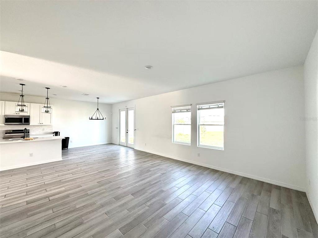 An open-concept living area features light wood-look flooring, white walls, and a kitchen island — 2077 DERWENT DRIVE, DAVENPORT, FL
