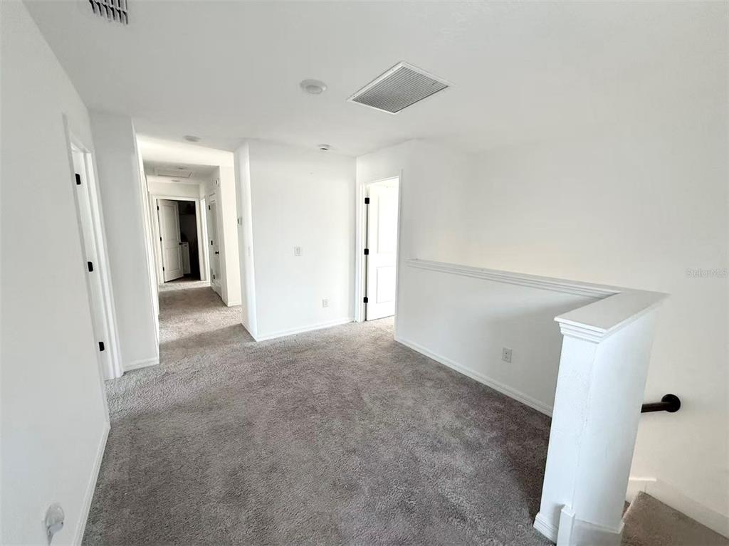 A carpeted hallway and landing area with white walls and several interior doors — 2077 DERWENT DRIVE, DAVENPORT, FL