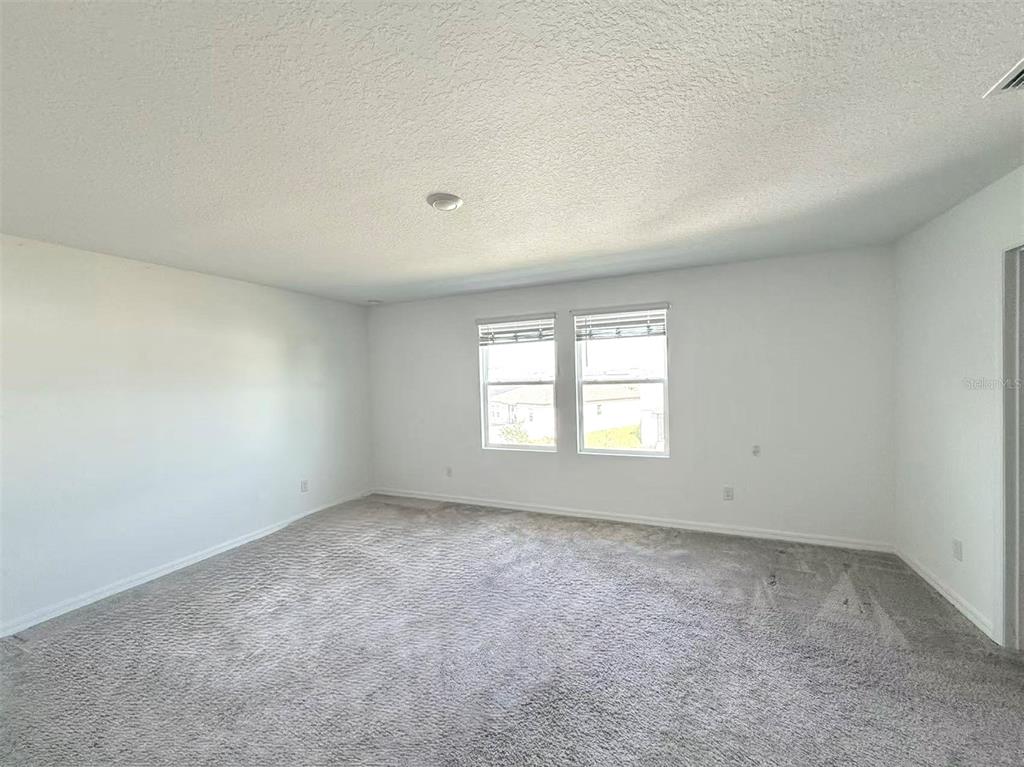 An empty room with gray carpet, white walls, and two windows — 2077 DERWENT DRIVE, DAVENPORT, FL