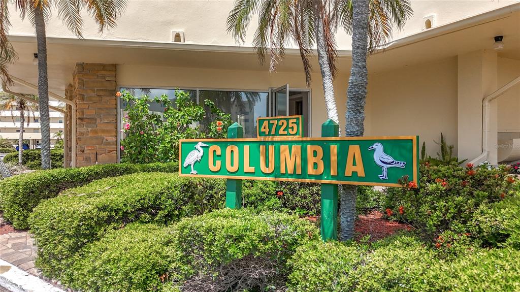 A green sign with the name Columbia stands in front of a building entrance — 4725 COVE CIRCLE UNIT 908, ST PETERSBURG, FL