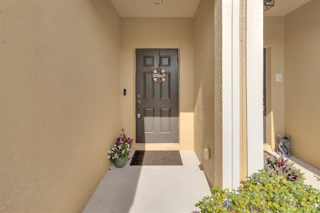 A covered entryway features a dark gray front door with a heart-shaped welcome sign — 13527 DANIELS LANDING CIRCLE, WINTER GARDEN, FL