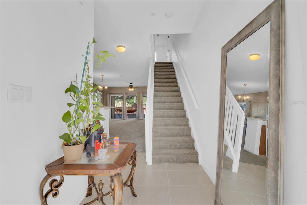 A foyer features a staircase with carpeted steps, a decorative console table, and a mirror — 13527 DANIELS LANDING CIRCLE, WINTER GARDEN, FL