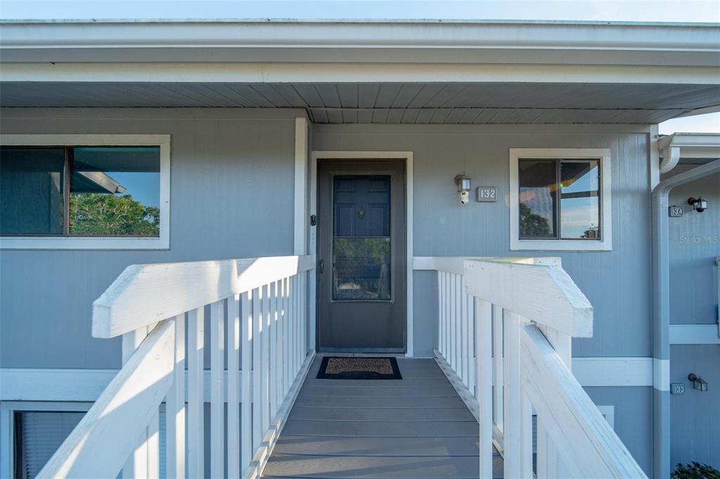 An exterior view of a building entrance with a wooden walkway and a gray door — 6033 34TH STREET W UNIT 132, BRADENTON, FL